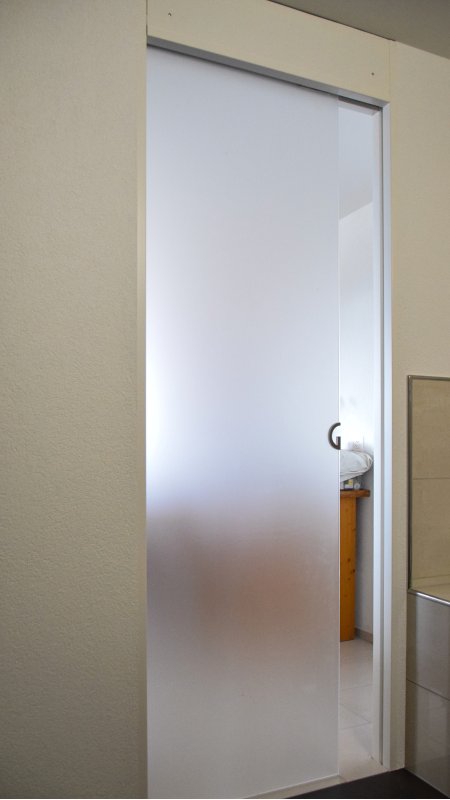 Die Schiebetür ersetzt die normale Tür. Türe in satiniertem Sicherheitsglas. Schönes Detail ist der eingearbeitete Griff.